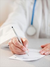 Close up of female doctor's hands writing prescription. Photo : Jamie Grill