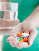 Close up of woman's hands holding pile of medicines. Photo : Jamie Grill