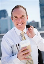 Smiling businessman with disposable cup. Photo : Jamie Grill