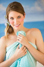 Portrait of young woman holding towel by sea.