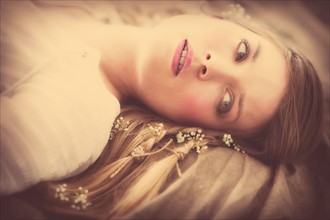Young woman lying with flowers in hair.