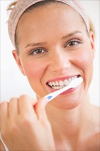 Studio portrait of woman brushing teeth.