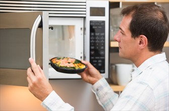 Man inserting meal in microwave oven.