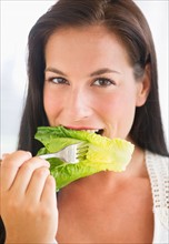 Portrait of woman eating lettuce.