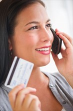 Woman holding credit card and phone.