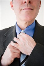 Close up of businessman tying tie. Photo : Jamie Grill