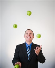 Businessman juggling apples. Photo : Jamie Grill