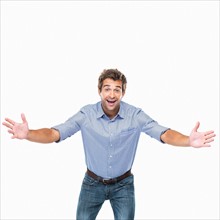 Studio shot of young cheerful man with arms outstretched. Photo : momentimages
