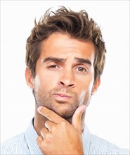 Close-up portrait of confused business man with had on chin against white background. Photo: