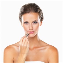 Studio portrait of beautiful woman applying lipstick. Photo : momentimages