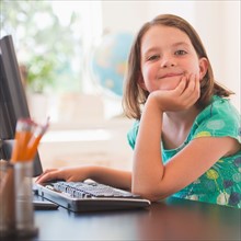 Portrait of girl (6-7) using computer in classroom. Photo: Daniel Grill