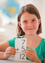 Portrait of girl (6-7) counting in classroom. Photo: Daniel Grill