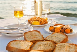 Greece, Cyclades Islands, Mykonos, Calamari appetizer on set table by sea.
