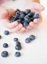 Close up of girl's (8-9) hands holding blueberries. Photo: Jamie Grill