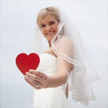 Happy bride holding red heart. Photo: Jamie Grill