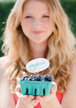 Young woman holding carton with organic blueberries. Photo: Jamie Grill