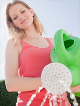 Young woman with watering can. Photo : Jamie Grill