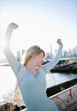 USA, Brooklyn, Williamsburg, Portrait of blonde woman stretching arms in backlit. Photo: Jamie