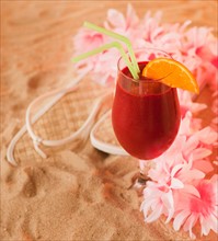 Close up of frozen drink and lei on sand. Photo: Daniel Grill