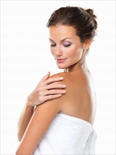 Studio portrait of young attractive woman wrapped in towel with hand on shoulder. Photo: