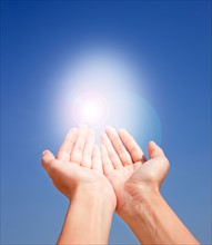 Close up of woman's hands holding sunlight on blue sky. Photo : Jamie Grill
