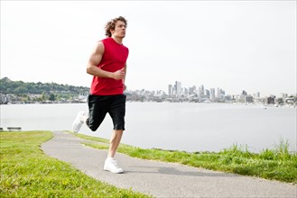 USA, Washington State, Seattle, Young man jogging along river. Photo : Take A Pix Media