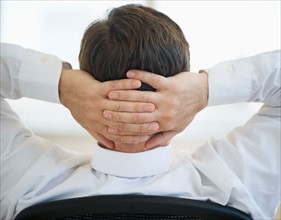 Businessman with hands behind head.