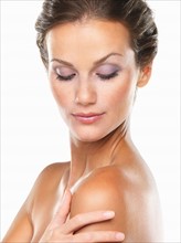 Studio shot of young attractive woman with hand on shoulder. Photo : momentimages