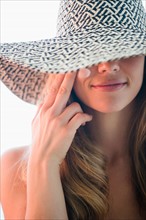 Portrait of woman in straw hat applying moisturizer. Photo: Jamie Grill