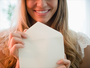 Portrait of blonde woman holding envelope. Photo : Jamie Grill
