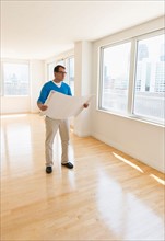 Architect reading blueprint in new office.