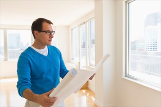 Architect reading blueprint in new office.