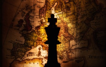 King chess piece on old world map.