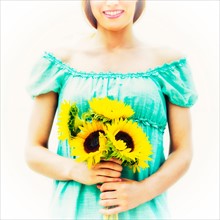 Young woman holding sunflowers.