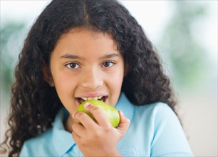 Portrait of girl (8-9) eating pear.