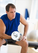 Mature man lifting weights in gym.