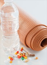 Exercise mat, water bottle and colorful pills, studio shot. Photo: Jamie Grill