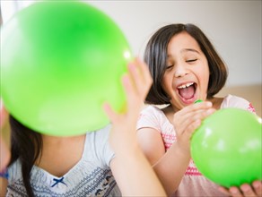 Close up of two girl's (8-9, 10-11) playing with green balloons. Photo: Jamie Grill