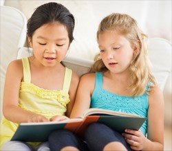 two girls (6-9) reading book.