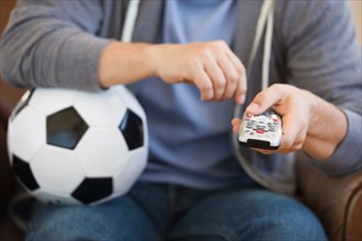 Man holding soccer ball and remote control.