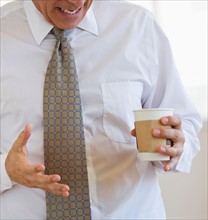 Businessman spilling coffee on shirt.