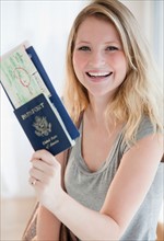 Young woman holding passports and plane tickets. Photo : Jamie Grill