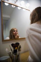 Reflection in mirror of woman doing make up. Photo: Jamie Grill