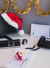 Close up of Santa hat and Christmas decorations on office desk. Photo : Daniel Grill