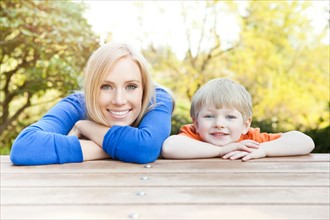 Portrait of mother and son (2-3) leaning at picnic table. Photo: Take A Pix Media