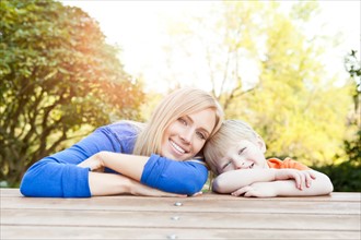 Portrait of mother and son (2-3) leaning at picnic table. Photo : Take A Pix Media