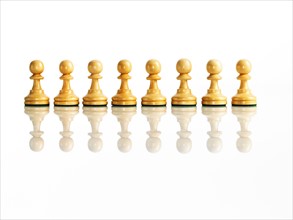 Wooden chess pawns in a row, studio shot. Photo: David Arky