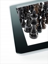 Studio shot of black chess queen and black chess pawns on tablet. Photo : David Arky