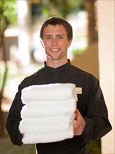 Man from room service delivering towels to hotel guest. Photo: db2stock