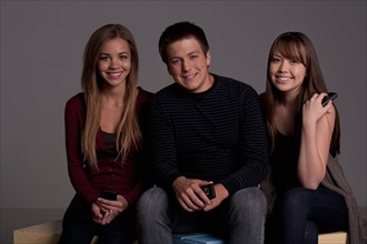 Portrait of teenage boy (16-17) and girl (16-17) with young friend, studio shot. Photo : Rob Lewine